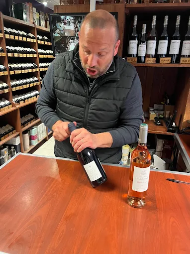 Sommelier de la cave As du Vin à Dijon débouchant une bouteille de vin rouge pour une dégustation client